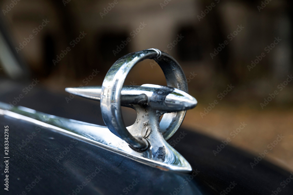 circular and futuristic chrome Bonnet mascot or hood ornament of black 1950's classic car close up circular and futuristic chrome Bonnet mascot or hood ornament of black 1950's classic car close up