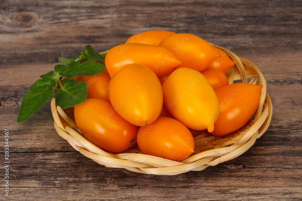 Yellow tomato heap in the wooden bowl