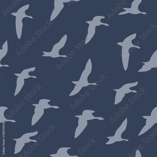 The seamless pattern with blue silhouettes of flying birds is on dark blue background.