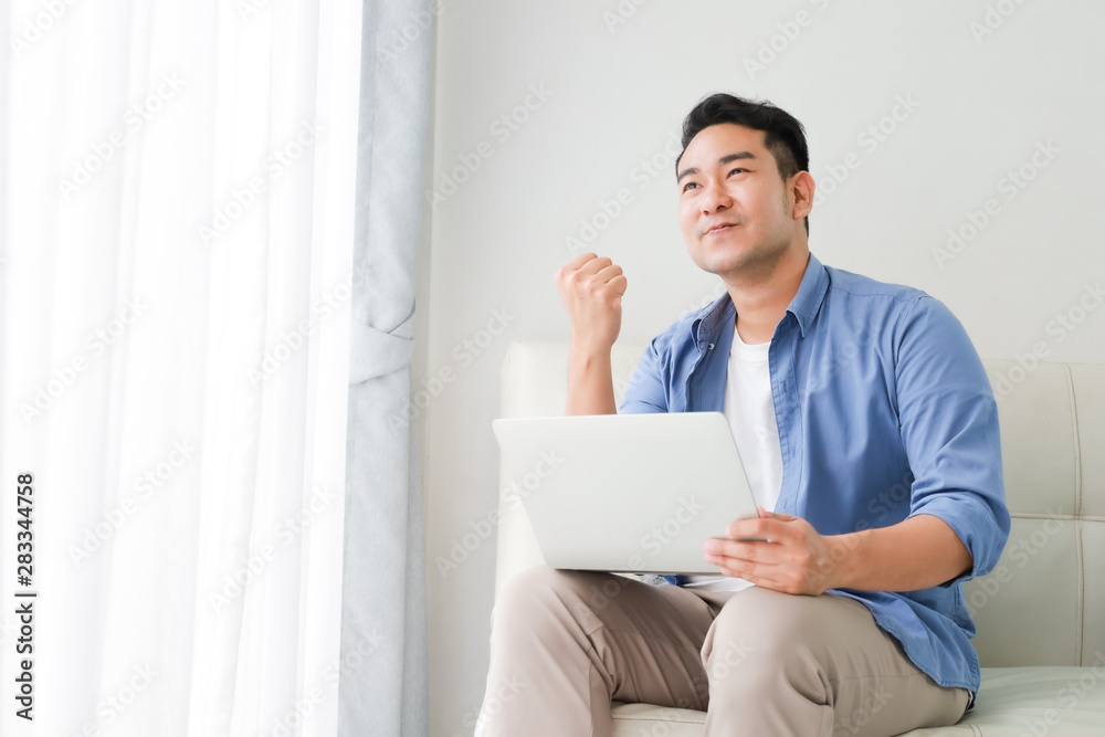 Asian handsome man working with laptop computer   in living room happy and smile face
