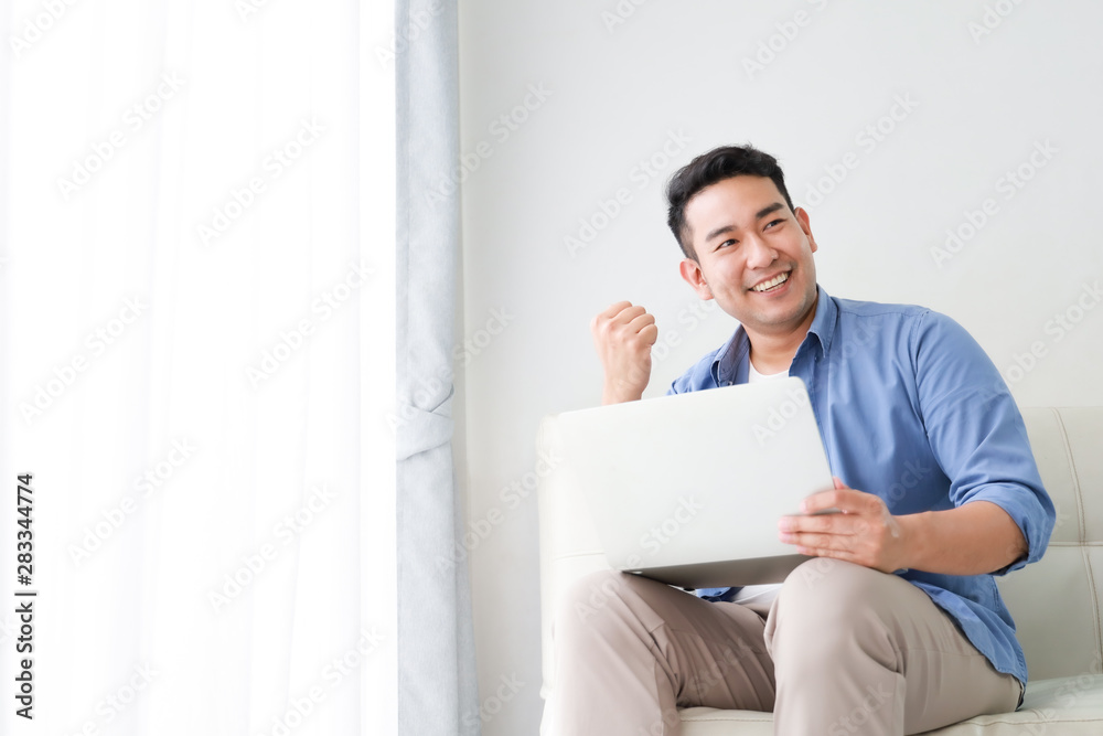 Asian handsome man working with laptop computer   in living room happy and smile face