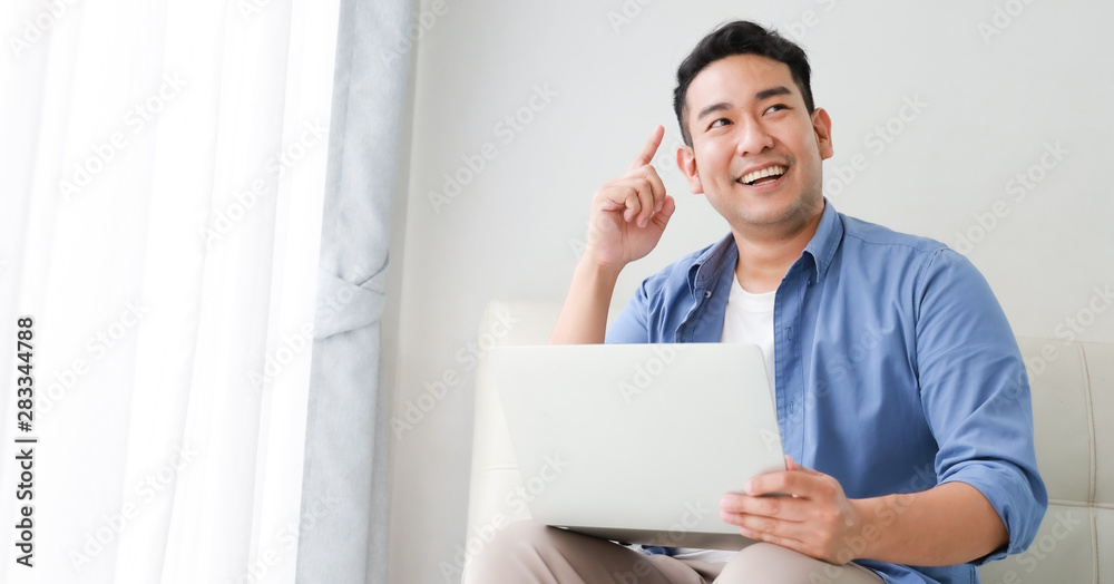 Asian handsome man working with laptop computer in living room happy and smile face Asian handsome man working with laptop computer in living room happy and smile face