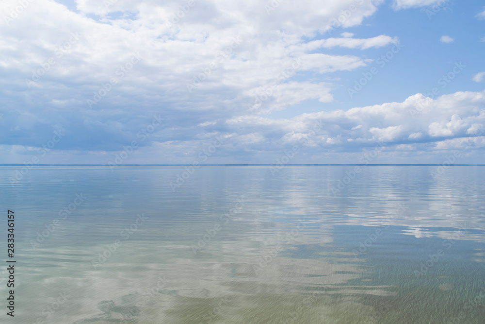Blue sky with clouds reflected in water. Beautiful seascape.