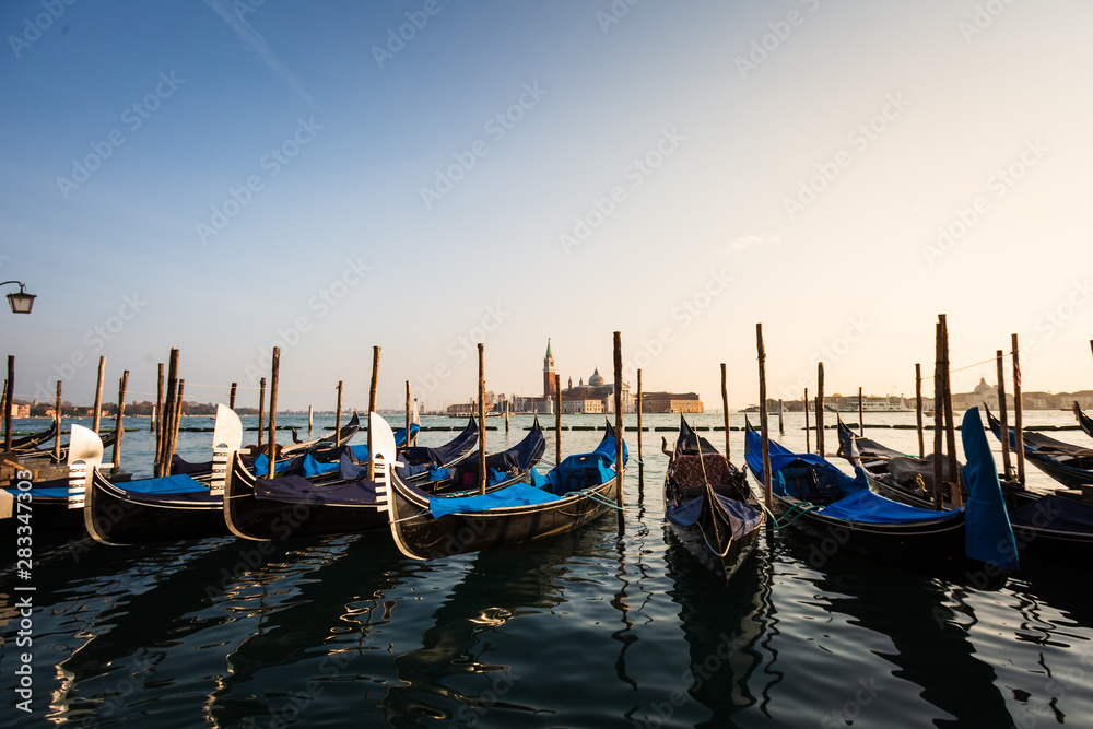 Gondolas in Venice sunset view with San Giorgio Maggiore church from San Marco square in Italy. Intentional motion blur.