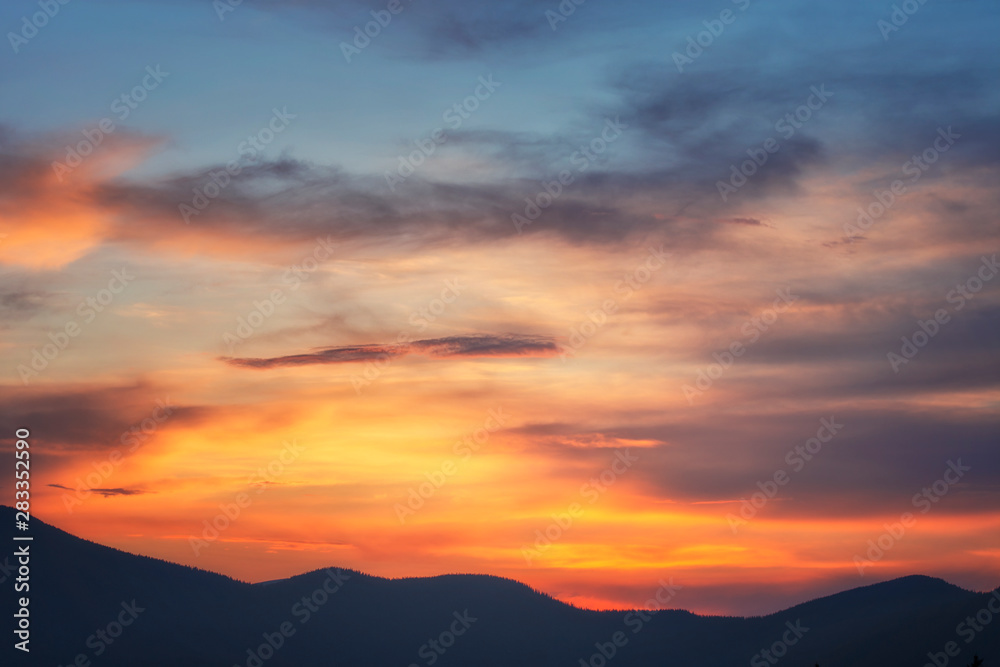 Background of bright sky at sunset. Mountain silhouettes.