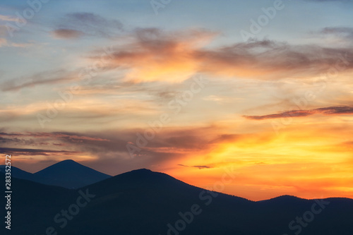 Background of bright orange sky at sunset. Mountain silhouettes.