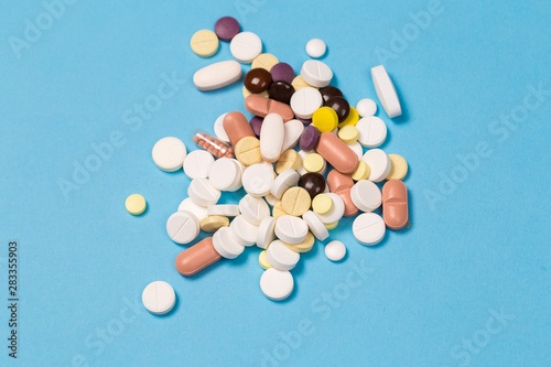many scattered Colorful medical pills on pastel blue background