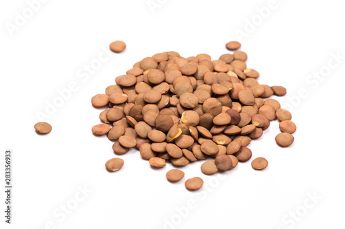 Isolated stack of uncooked lentils on white background from above.