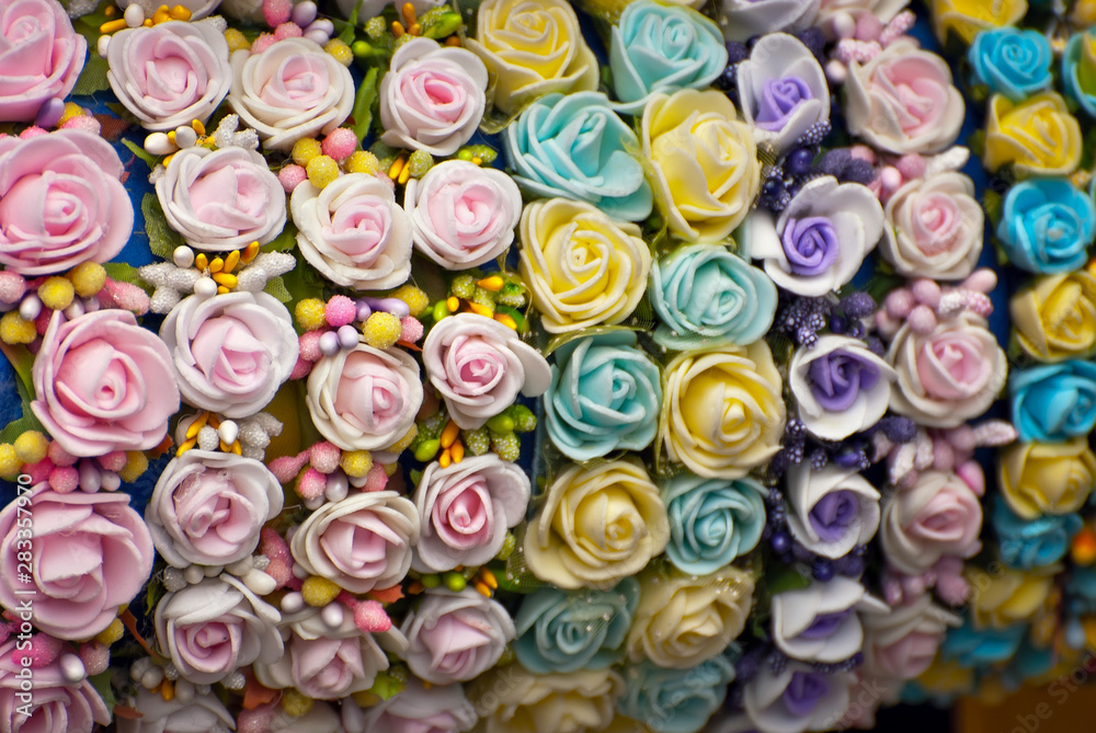 Bouquets of artificial flowers are sold at the fair. Corollas of colored small flowers. Closeup of national decorations and accessories for clothing.
