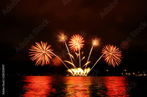 Beautiful colorful fireworks in sky over river. Big festive evening event with great pyrotechnic show.  