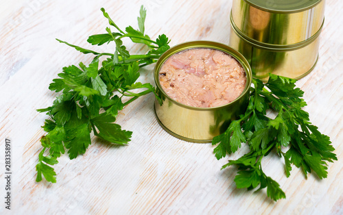 Canned tuna with parsley and lemon on a wooden table photo