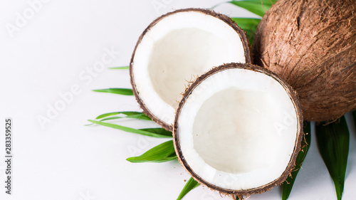 Ripe half cut coconut with green leaves on a white background. Isolated concept.