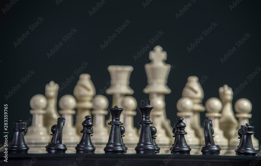 Tiny White set facing Black set in 10 times size. Both standing against each other on the chess board ready to fight. Size has no matter about the rule to play but it looks scary. Local vs. Global. Sm