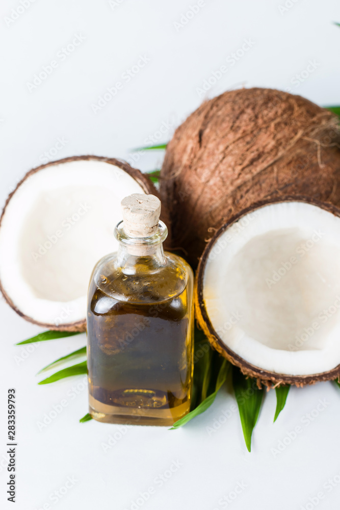 Ripe half cut coconut and oil with green leaves on a white isolated background. Healthcare and medical concept. Skin care. Ripe half cut coconut and oil with green leaves on a white isolated background. Healthcare and medical concept. Skin care.