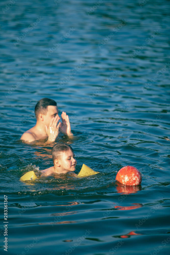 father with kid having fun in water swimming together