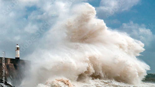 Obraz na plátně Huge ocean waves crashing into a sea wall and lighthouse (Porthcawl, South Wales