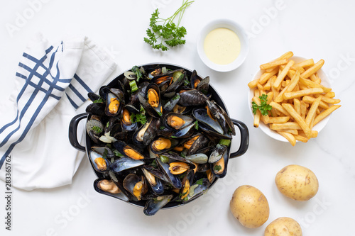 Belgian mussels with potato fries on white marble surface flat lay view 