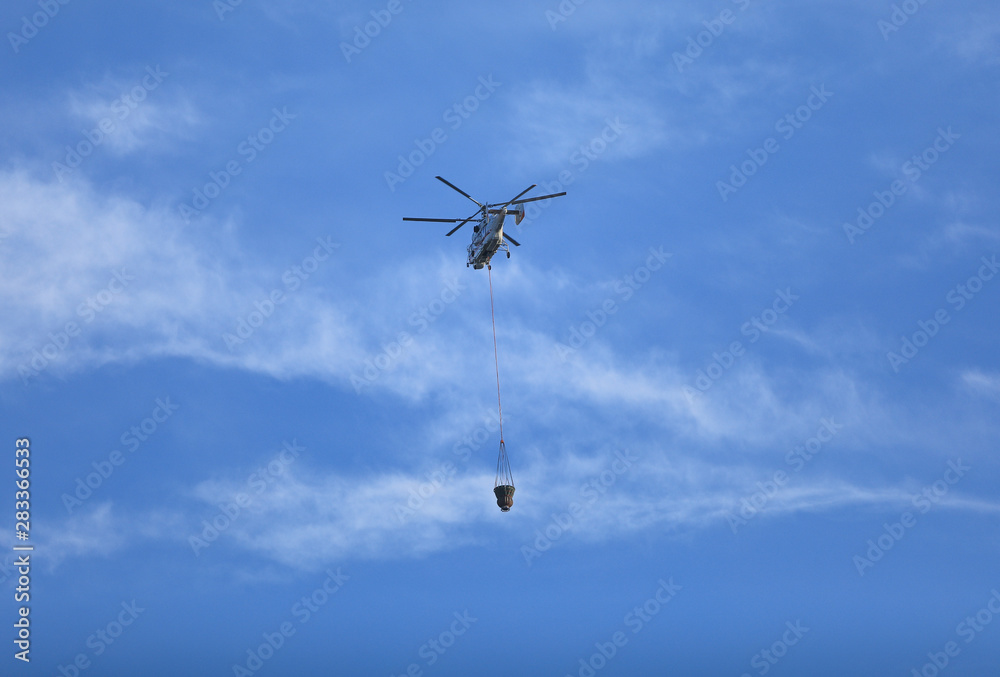 Fire fighting helicopter with waterbag on his way to combat the fire Fire fighting helicopter with waterbag on his way to combat the fire