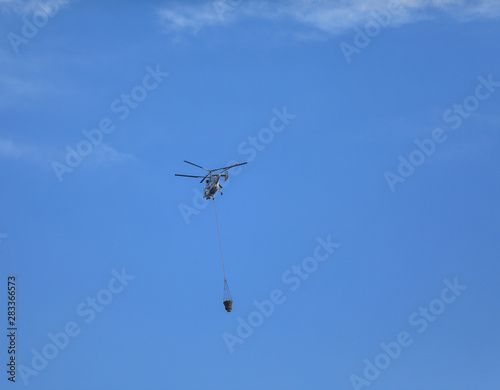 Fire fighting helicopter with waterbag on his way to combat the fire