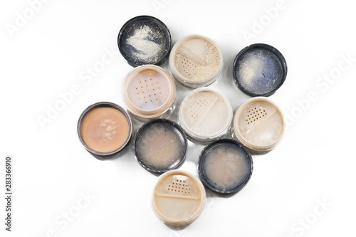 Close-up of makeup jars filled with loose cosmetic face powder different shades on the white background isolated. Free space for text mockup