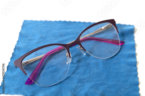 Stylish glasses lie on a blue cloth for cleaning. Isolated