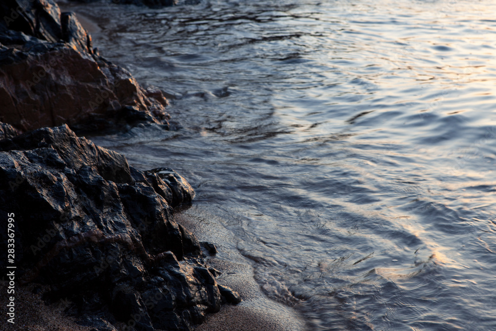 sunrise light over stones, sand and water sunrise light over stones, sand and water