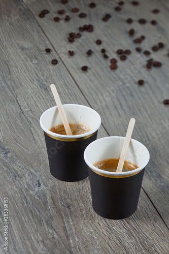 Two cups of espresso on a wooden background with coffee beans. Environmentally friendly material. Close up.