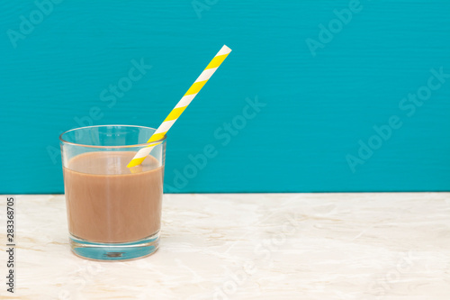 Thick chocolate milkshake with a straw in a glass