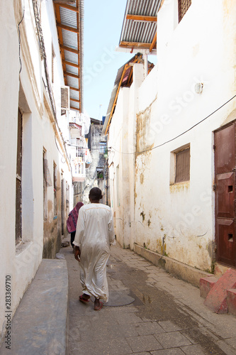 alleyway scene with daily commuters moving through the streets of stone town zanzibar © mikefoto58