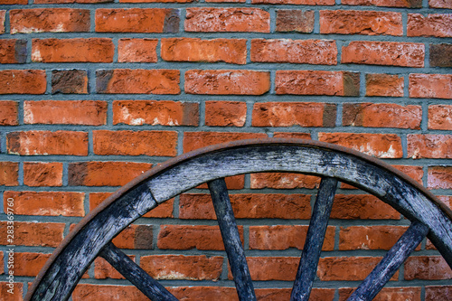 old wooden wheel in the front of bricks wall, creative background