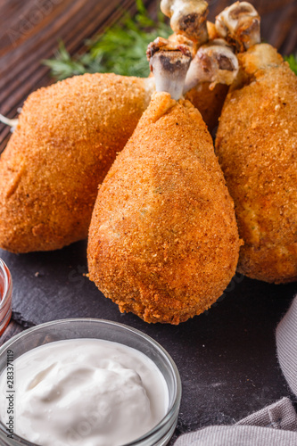 fried chicken leg in batter, red and white sauce on a dark surface photo