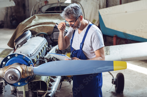 Aircraft maintenance mechanic inspects plane engine