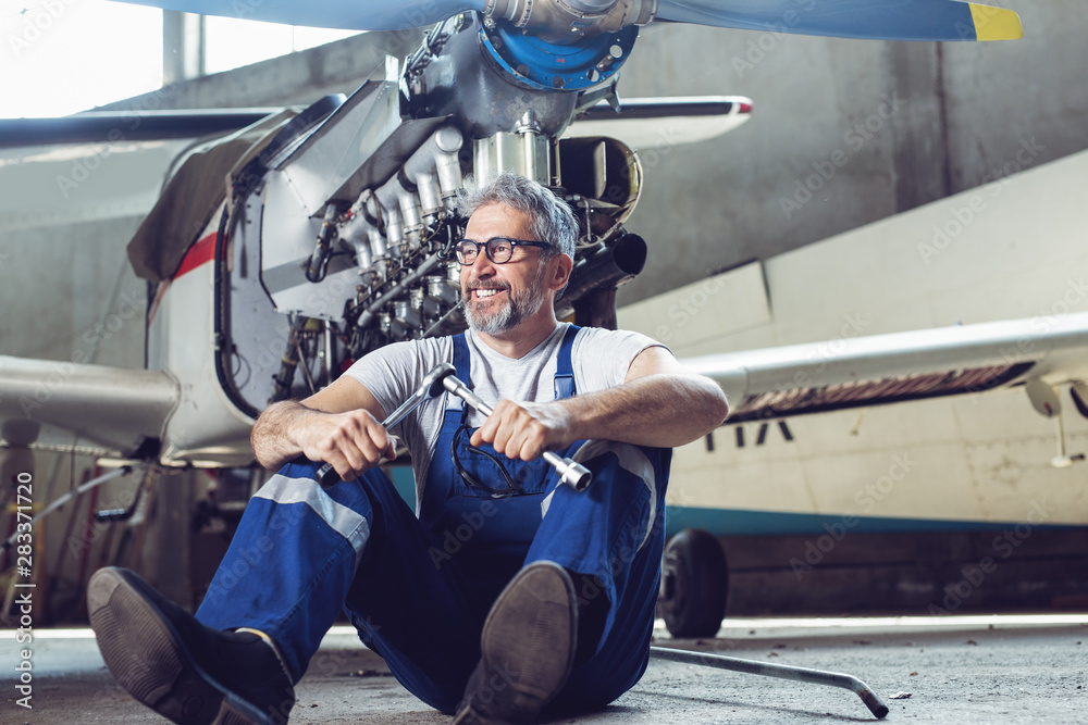 Aircraft mechanic repairs an aircraft engine in an airport hangar Aircraft mechanic repairs an aircraft engine in an airport hangar