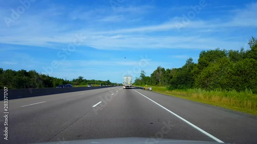 Drafting Large Truck on Highway During Summer Day.  Driver Point of View POV Slipstreaming by Following Vehicle on Interstate or Freeway or Expressway or Motorway or Turnpike.