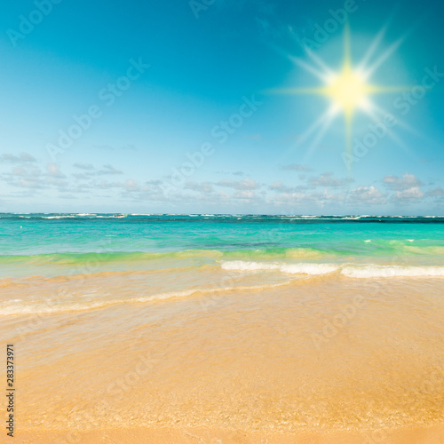 Sunny tropical caribbean beach with sand and turquoise water.