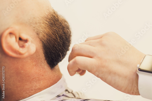 Bearded man, brutal, getting stylish hair shaving, haircut, with razor by barber or hairdresser at barbershop