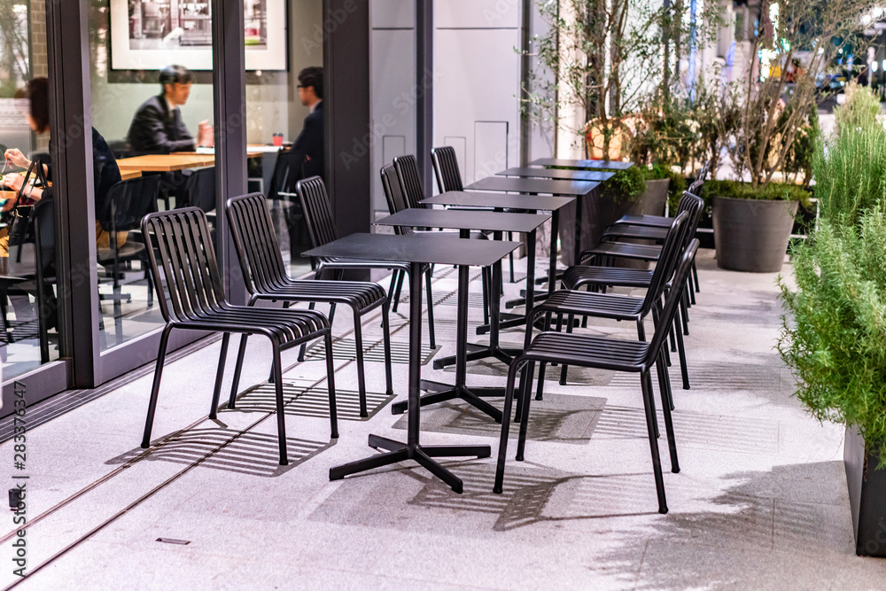 Black shiny steel chairs and wooden tables in indoor industrial and modern style canteen