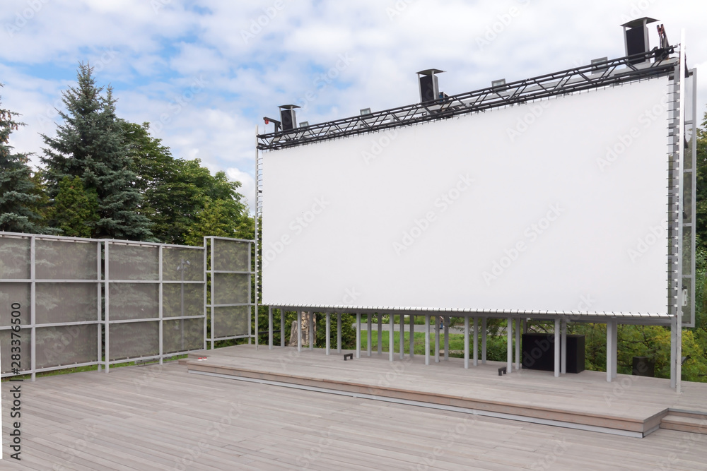 Outdoor empty movie cinema theater with white projection screen in the park, waiting for the show with copy space Outdoor empty movie cinema theater with white projection screen in the park, waiting for the show with copy space