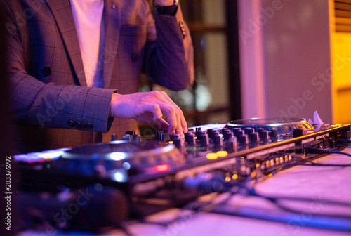 DJ hands on stage mixing, disc jockey and mix tracks on sound mixer controller, playing music for party at night club. © Ruthsarintre