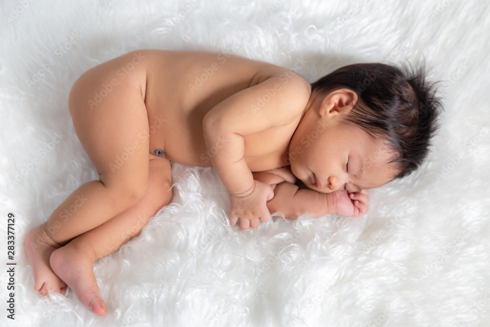 Cute asian new born baby girl or infant girl is asleep and undressed.  Adorable newborn baby