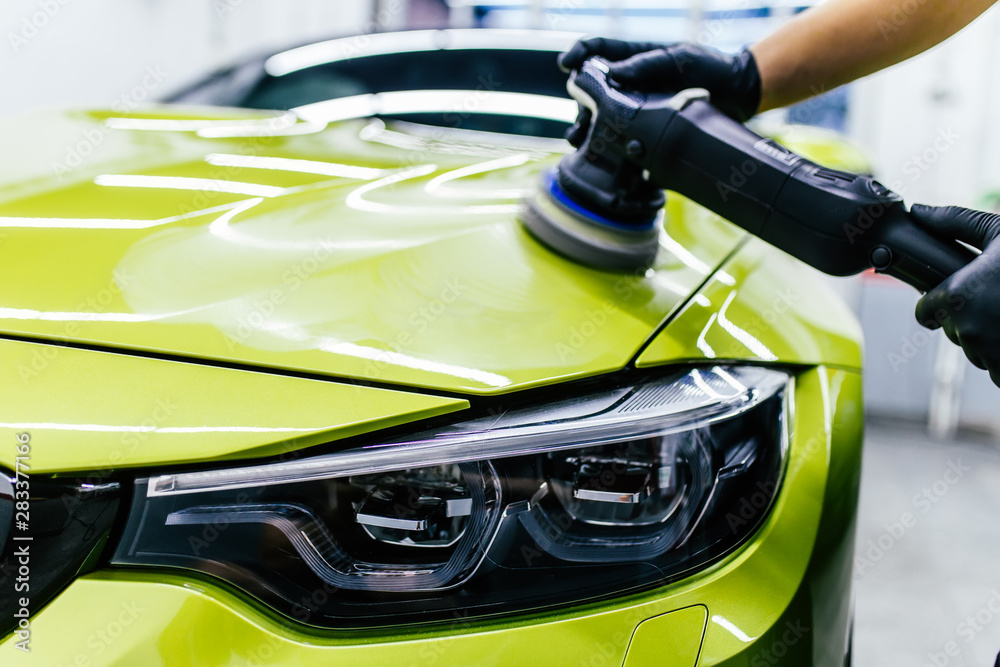 Car detailing - Worker with orbital polisher in auto repair shop. Car detailing - Worker with orbital polisher in auto repair shop.
