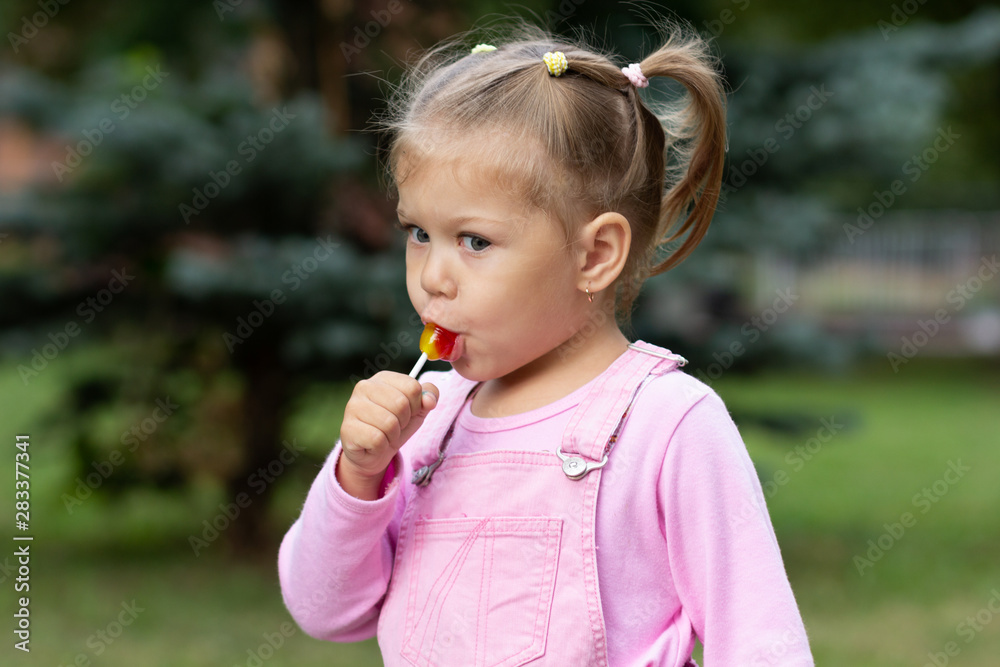Beautiful child with lollipop in the summer park Beautiful child with lollipop in the summer park