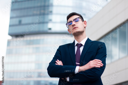 Valokuva Serious arrogant young businessman in a suit with tie and in glasses looking dow