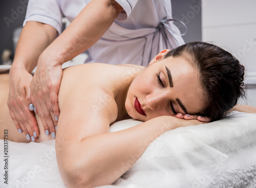 Beautiful young woman enjoying massage in spa salon. Cosmetology