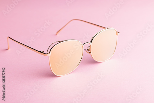 Classic aviator mirrored flat lens sunglasses with golden metal frame closeup on pink background