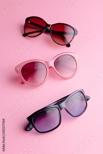 Collection of fashionable sunglasses on pink background. Sunglasses of different shapes and colors flat lay