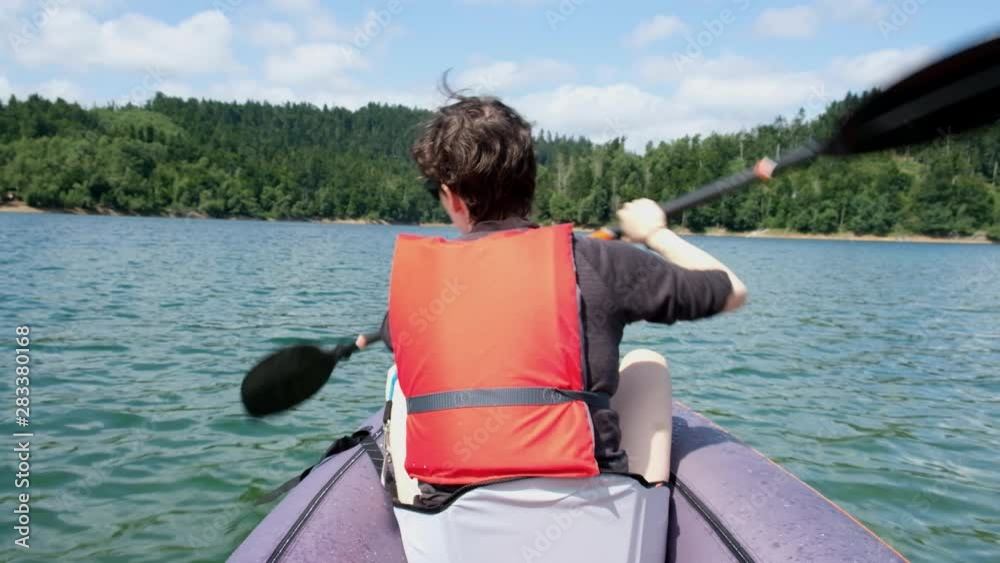 Young woman kayaking inflatable kayak on lake Lokve, in Gorski kotar, Croatia. Adventurous water sport experience on a beautiful sunny summer day. Young woman kayaking inflatable kayak on lake Lokve, in Gorski kotar, Croatia. Adventurous water sport experience on a beautiful sunny summer day.