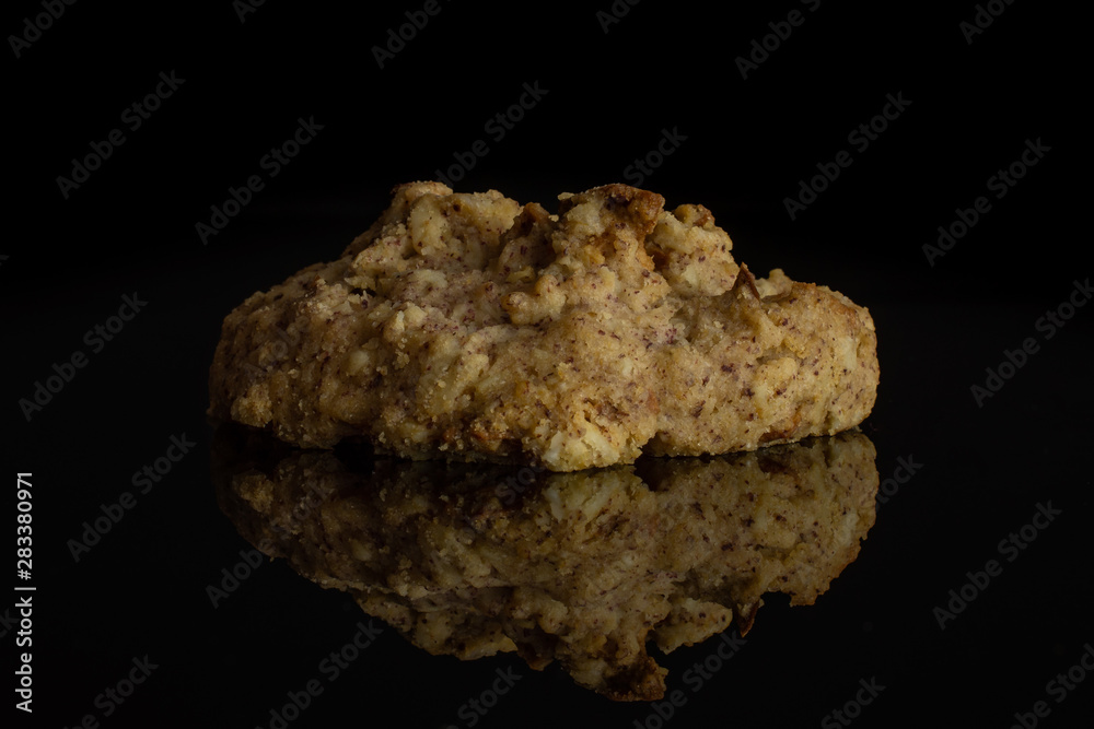 One whole oat crumble biscuit isolated on black glass One whole oat crumble biscuit isolated on black glass