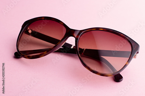 Classic oval oversized brown tortoise sunglasses closeup on pink background