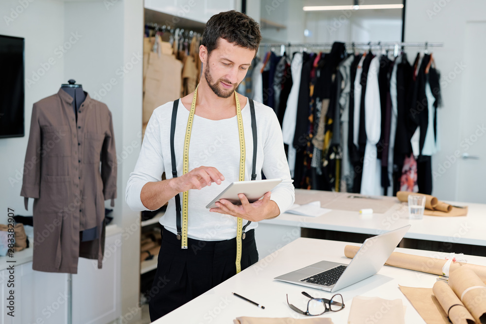 Fototapeta premium Young man concentrating on networking while scrolling in touchpad